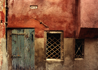 Color photograph of a painted Venetian door and wall with a fenced window
