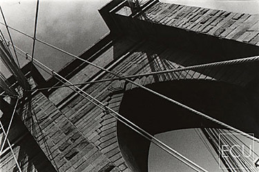 Black and white photo of the landmark Brooklyn Bridge stone arch and cable worm's eye view taken from the walkway in New York, New York